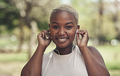 Buy stock photo Shot of a young woman using her earphone to listen to music during a workout