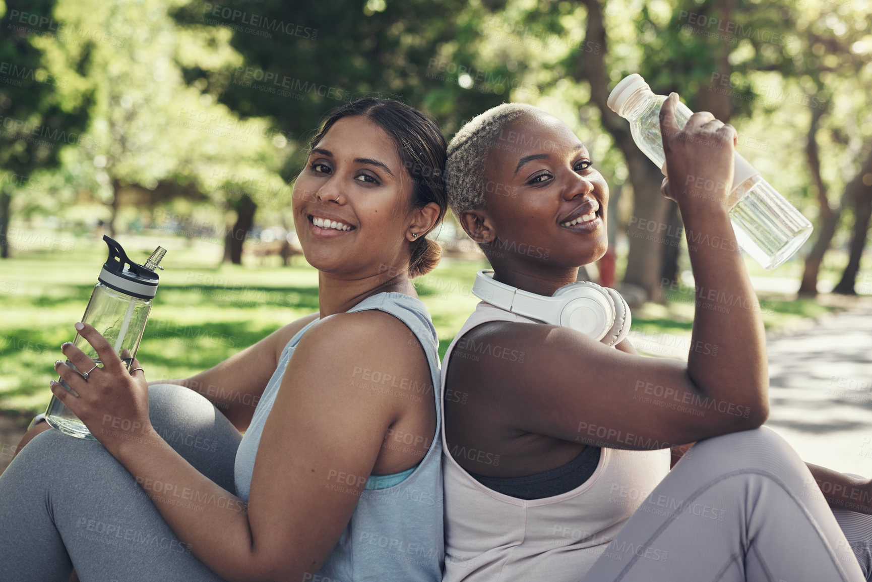 Buy stock photo Shot of two friends taking a break during their workout