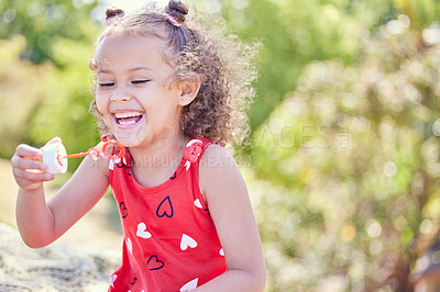 Buy stock photo Shot of an adorable little girl blowing bubbles at the park
