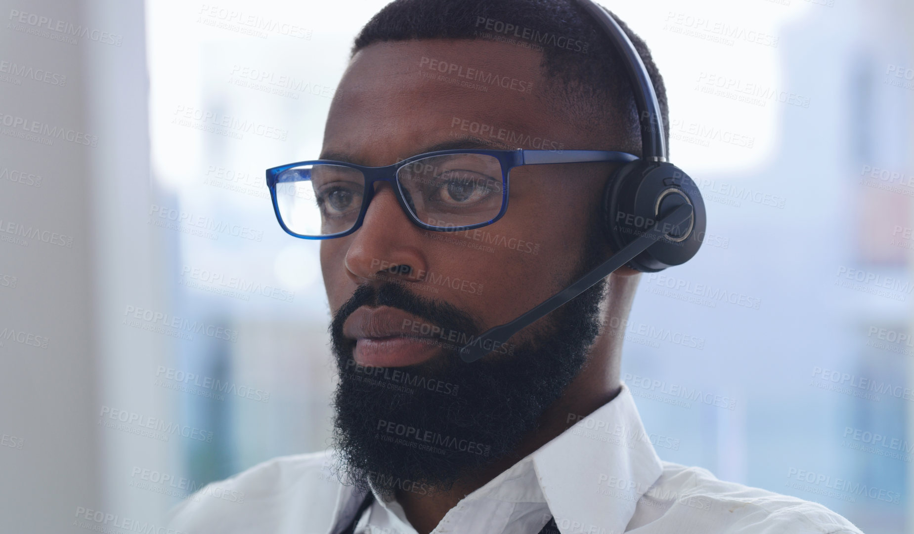 Buy stock photo Shot of a young businessman wearing a headset while working in an office