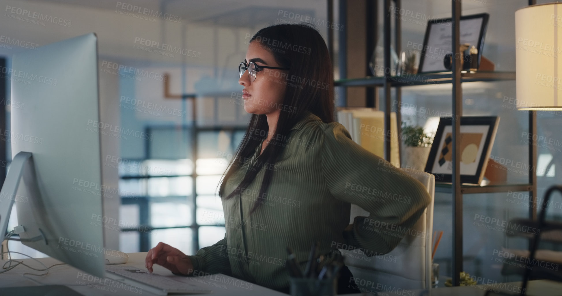 Buy stock photo Business woman, back pain and computer at night in office with stress, burnout or crisis. Female entrepreneur at a desk with tech, fatigue and backache while tired of deadline or internet problem