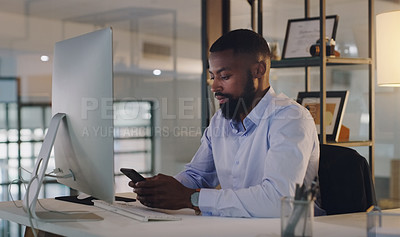 Buy stock photo Shot of a young businessman using a cellphone while working in an office at night