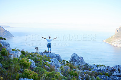 Buy stock photo Rearview shot of an unrecognizable young man and his pet husky taking in the views during their early morning hike in the mountains