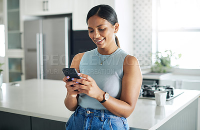 Buy stock photo Smile, phone and woman in kitchen networking on website, internet or mobile app at home. Technology, happy and young female person typing online email on cellphone by counter in modern apartment.