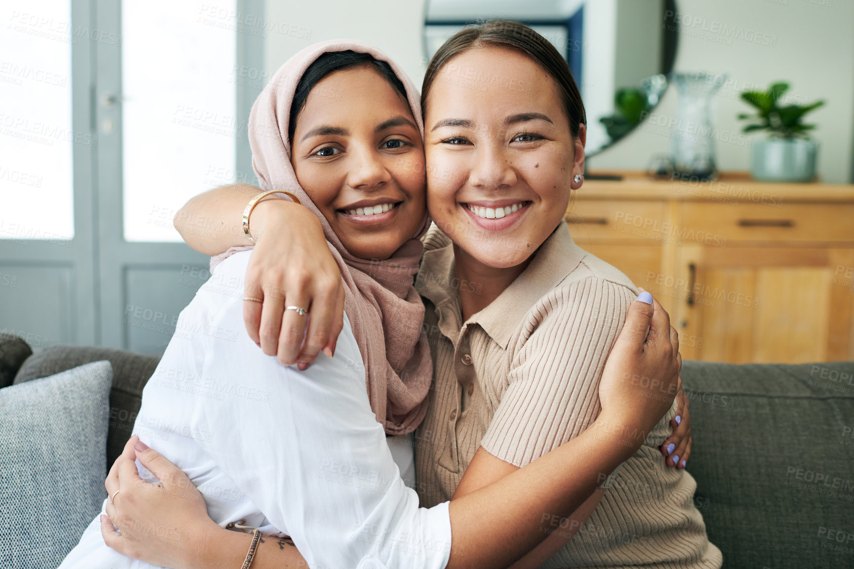 Buy stock photo Diversity, portrait and women hugging on sofa in living room of home together for bonding or visit. Love, relax and smile with happy young friends embracing in apartment for peace, support or trust