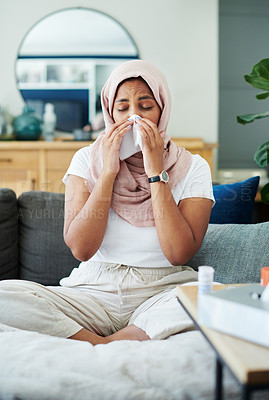 Buy stock photo Muslim, woman and sick or sneezing on couch in living room with illness, flu and tired at home. Female person, lounge and fever with medication to relax, chill and calm on sofa for recovery or rest

