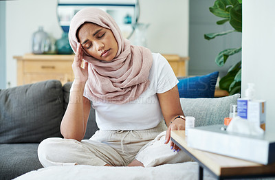 Buy stock photo Woman, muslim and headache or sick in home, cold and medicine for illness and treatment for health. Female person, hijab and migraine on couch for burnout, pills and stress for crisis or head pain