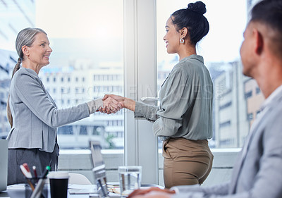Buy stock photo Shot of two businesswomen shaking hands during a meeting in an office