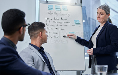 Buy stock photo Shot of a mature businesswoman using a whiteboard during a presentation to her colleagues in an office