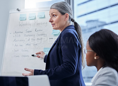 Buy stock photo Shot of a mature businesswoman using a whiteboard during a presentation to her colleagues in an office