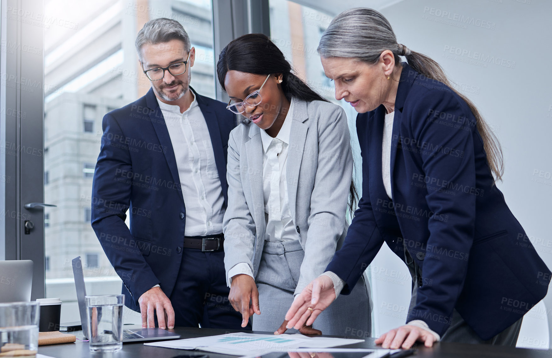 Buy stock photo Shot of a group of businesspeople going through paperwork together in an office