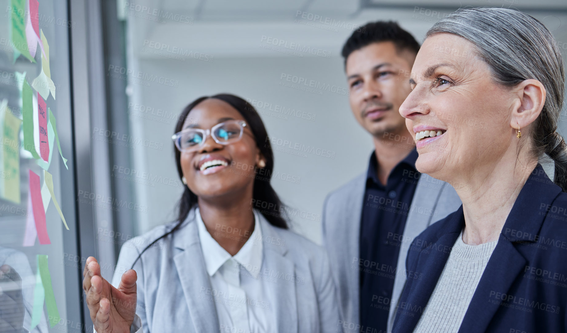 Buy stock photo Shot of a group of businesspeople brainstorming with notes on a glass wall in an office