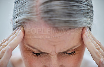 Buy stock photo Cropped shot of a mature businesswoman sitting alone in the office and suffering from a headache