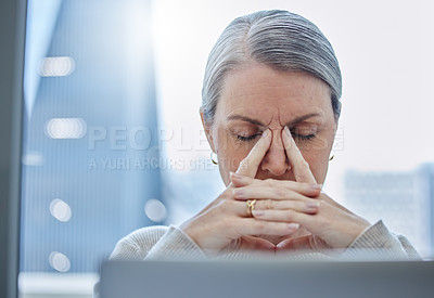 Buy stock photo Shot of a mature businesswoman sitting alone in the office and feeling stressed