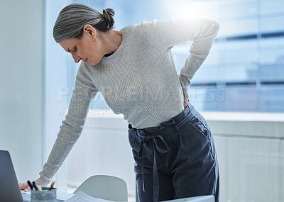 Buy stock photo Shot of a mature businesswoman standing alone in the office and suffering from backache