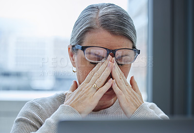 Buy stock photo Shot of a mature businesswoman sitting alone in the office and suffering from a headache