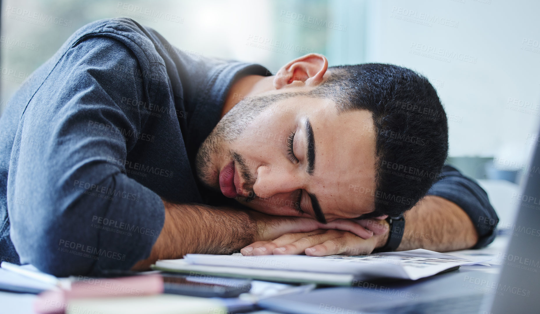 Buy stock photo Shot of a young businessman feeling exhausted and sleeping on his desk in his office