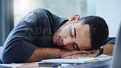 Buy stock photo Shot of a young businessman feeling exhausted and sleeping on his desk in his office