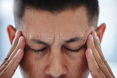 Buy stock photo Cropped shot of a young businessman sitting alone in the office and suffering from a headache