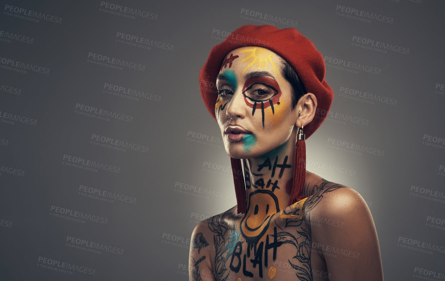 Buy stock photo Studio shot of a young woman posing with paint on her face on a grey background