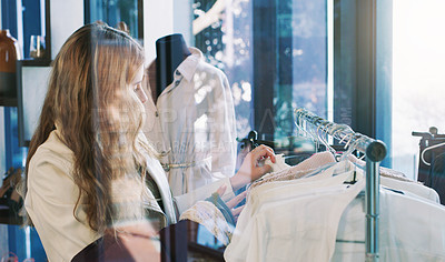 Buy stock photo Shot of a young woman browsing through clothes in a boutique
