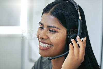 Buy stock photo Shot of an attractive young saleswoman sitting alone in her office and wearing a headset