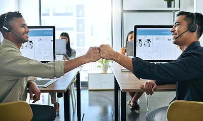 Buy stock photo Shot of two handsome salesmen sitting together in the office and giving each other a fist bump