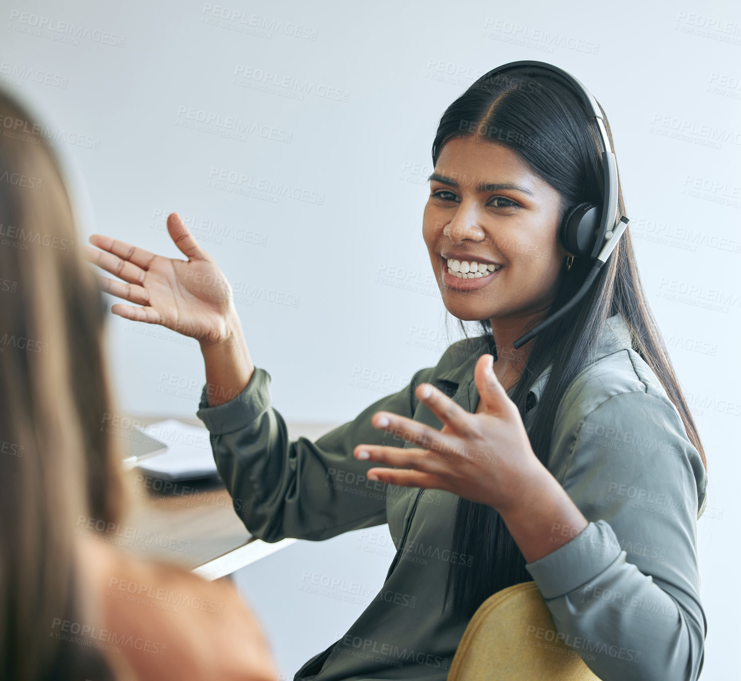 Buy stock photo Shot of an attractive young saleswoman sitting in the office with a colleague and wearing a headset