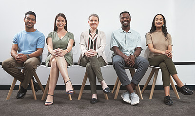 Buy stock photo Portrait of a group of businesspeople sitting together in a line against a white wall