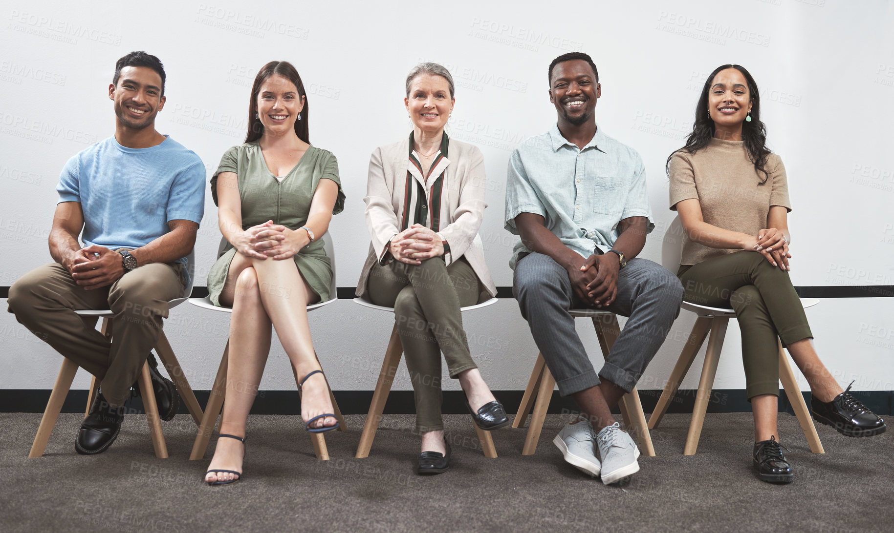 Buy stock photo Portrait of a group of businesspeople sitting together in a line against a white wall