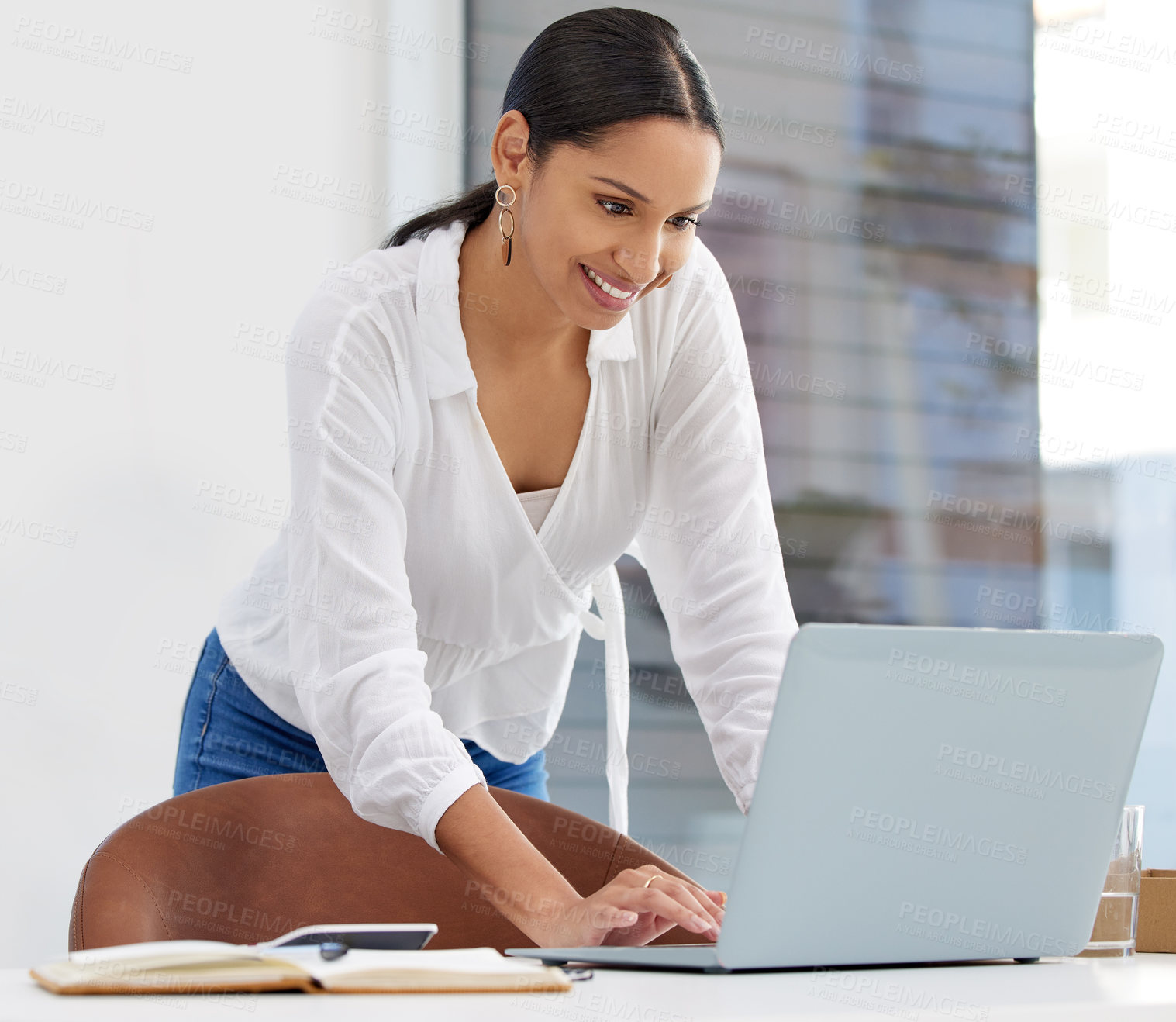 Buy stock photo shot of a young businesswoman using a laptop in a modern office