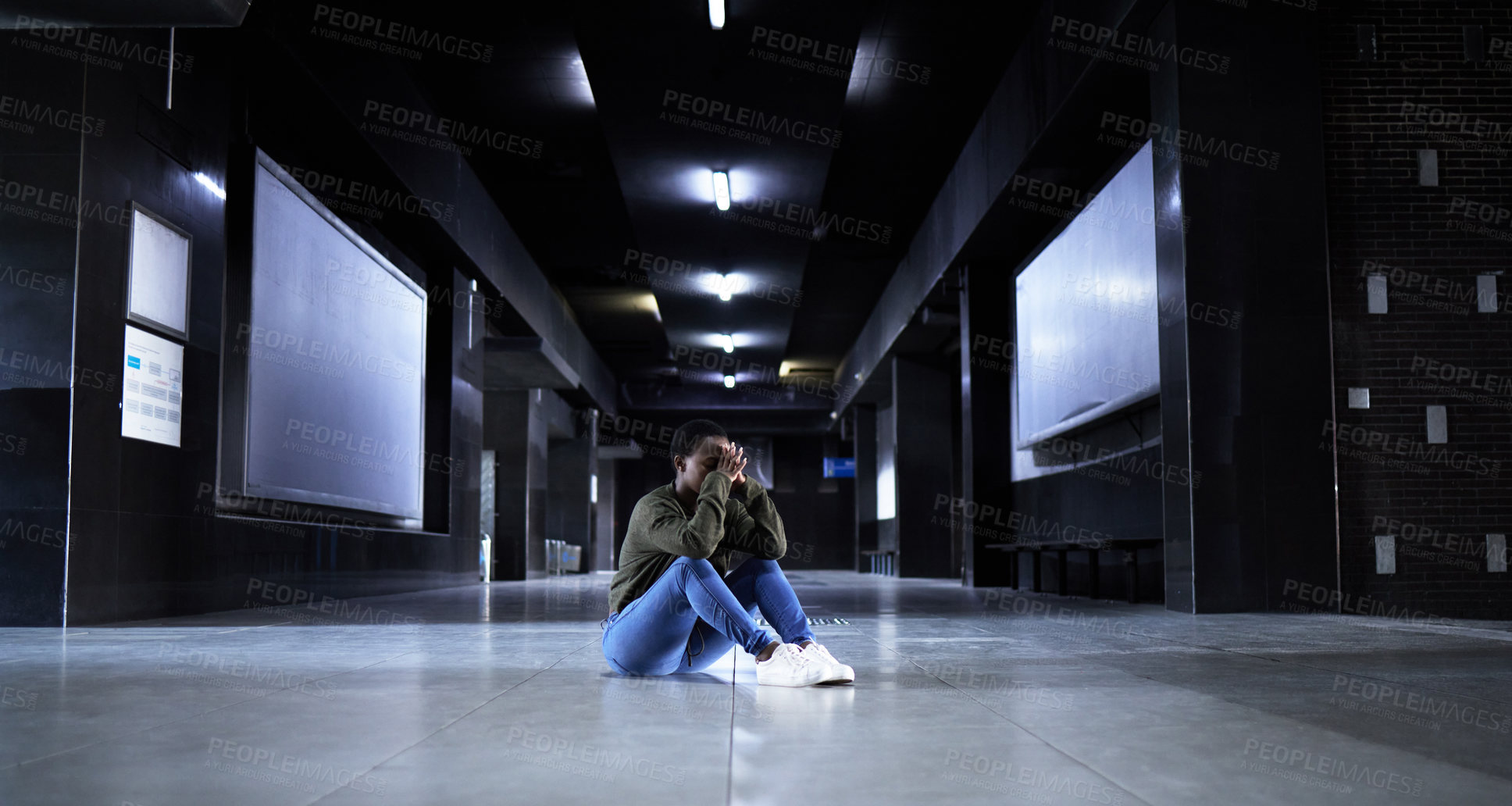 Buy stock photo Full length shot of a young woman looking depressed while sitting on the floor of a train station terminal