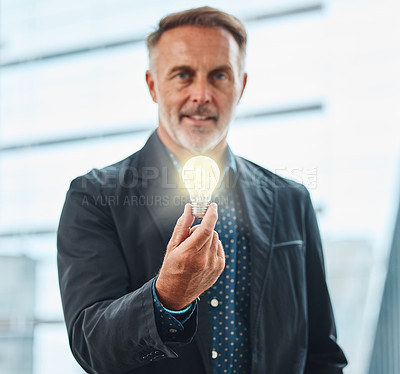 Buy stock photo Shot of a mature businessman holding a lightbulb against an urban background