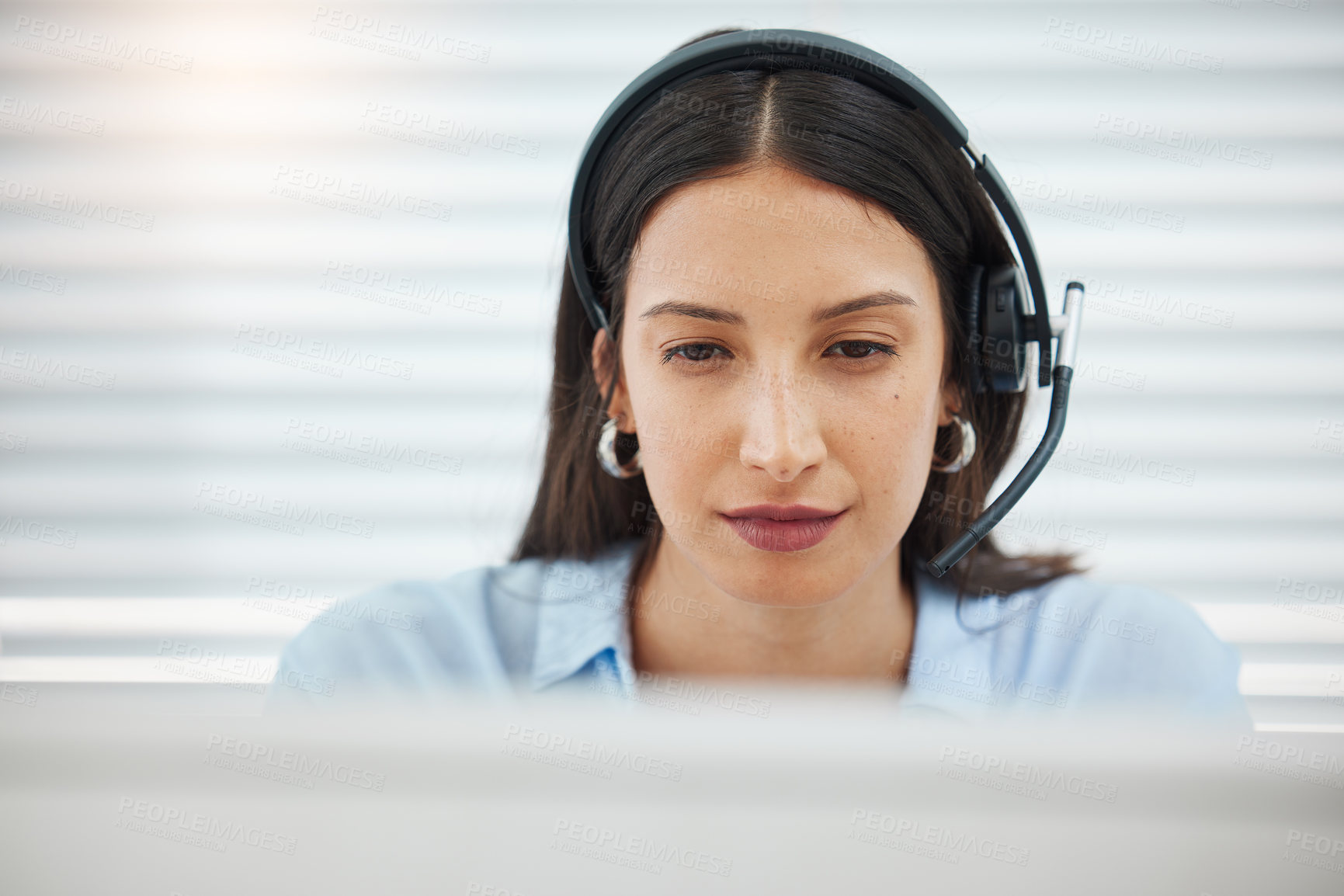 Buy stock photo Shot of an attractive young saleswoman sitting alone in her office and wearing a headset