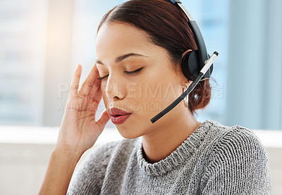 Buy stock photo Shot of an attractive young saleswoman sitting alone in her office and suffering from a headache