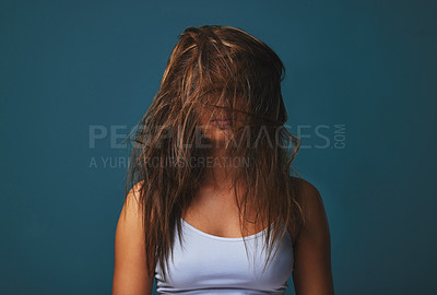 Buy stock photo Studio shot of a young woman covering her face with her hair posing against a blue background