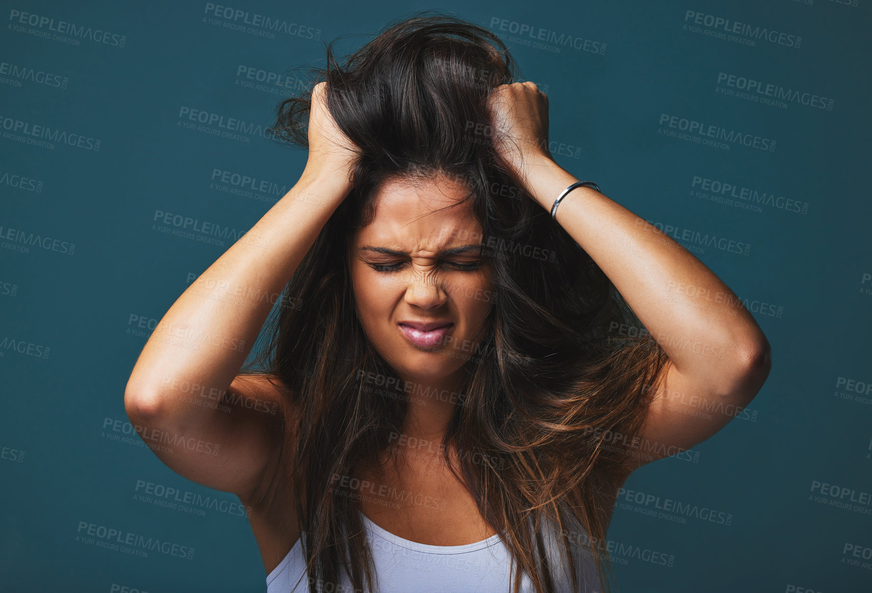 Buy stock photo Studio shot of a beautiful young woman with her hands in her hair posing against a blue background