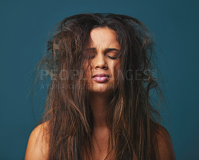 Buy stock photo Studio shot of a beautiful young woman with messy hair posing against a blue background
