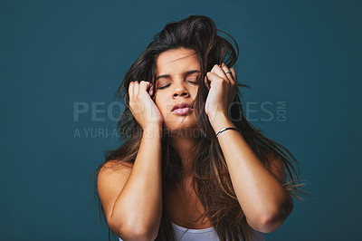 Buy stock photo Studio shot of a beautiful young woman with her hands to her face posing against a blue background