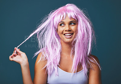 Buy stock photo Studio shot of a beautiful young woman posing with a playful pink wig against a blue background