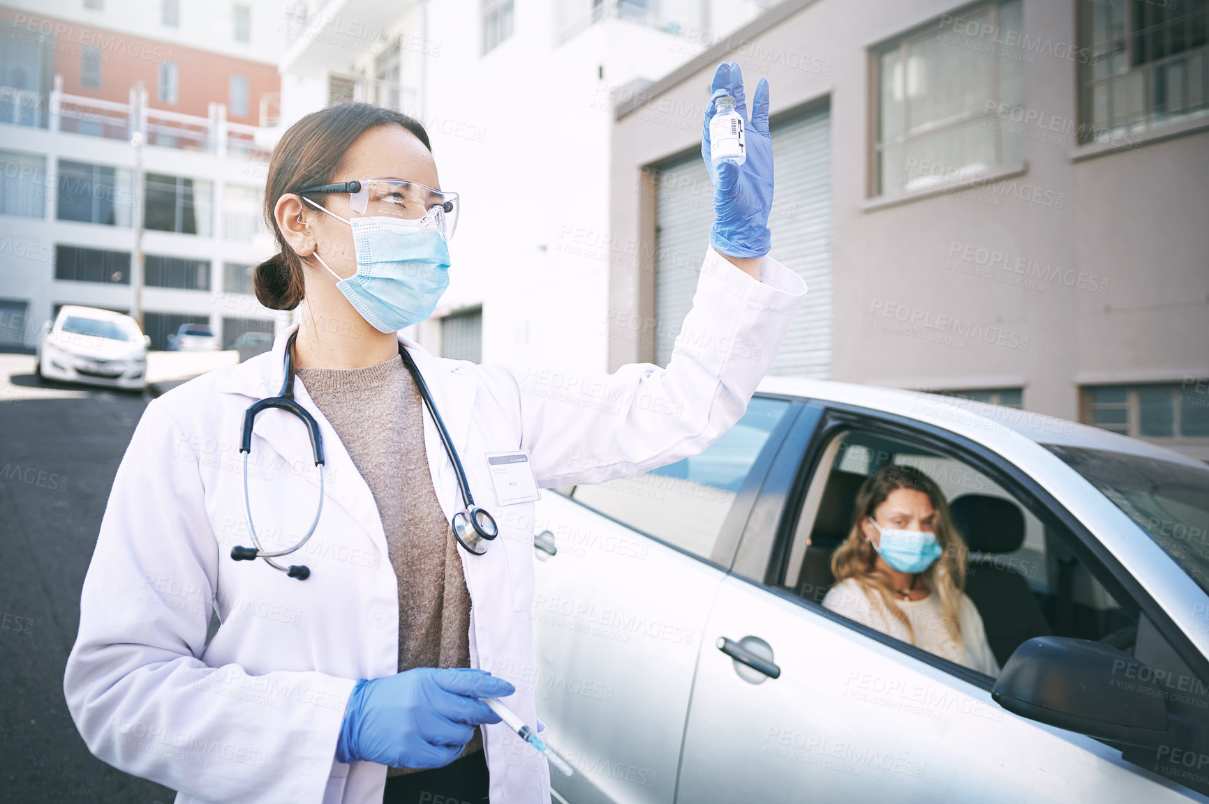 Buy stock photo Shot of a masked young doctor giving a patient an injection at a Covid-19 drive through testing centre