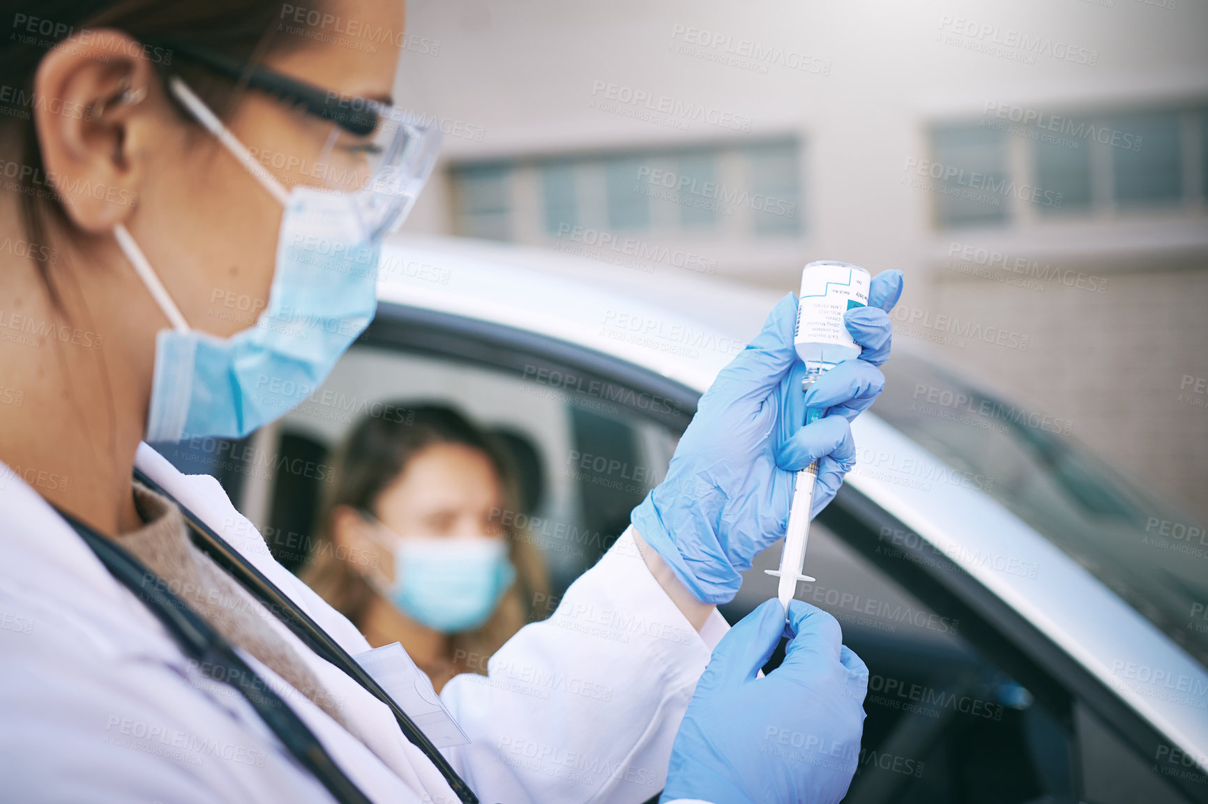 Buy stock photo Shot of a masked young doctor giving a patient an injection at a Covid-19 drive through testing centre