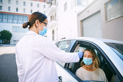 Buy stock photo Shot of a masked young woman getting her temperature checked by a doctor while sitting in her car