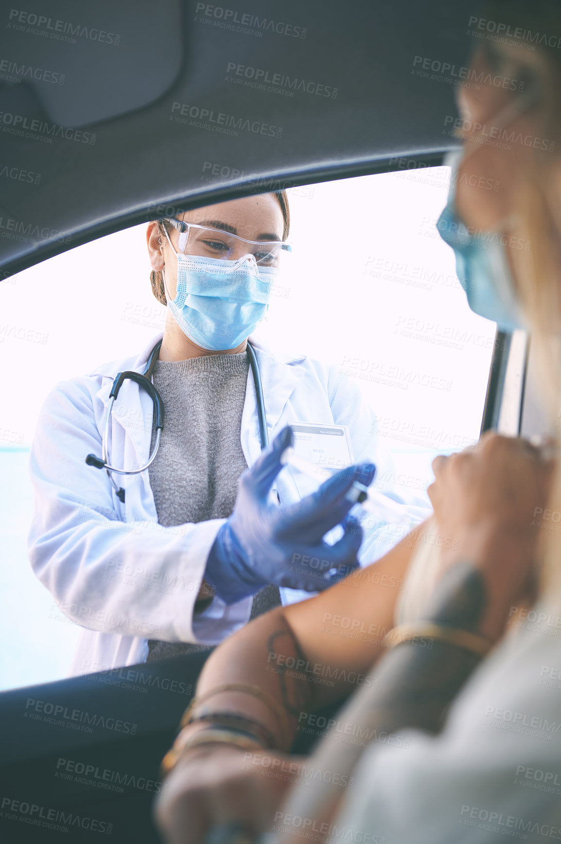 Buy stock photo Shot of a masked young doctor giving a patient an injection at a Covid-19 drive through testing centre