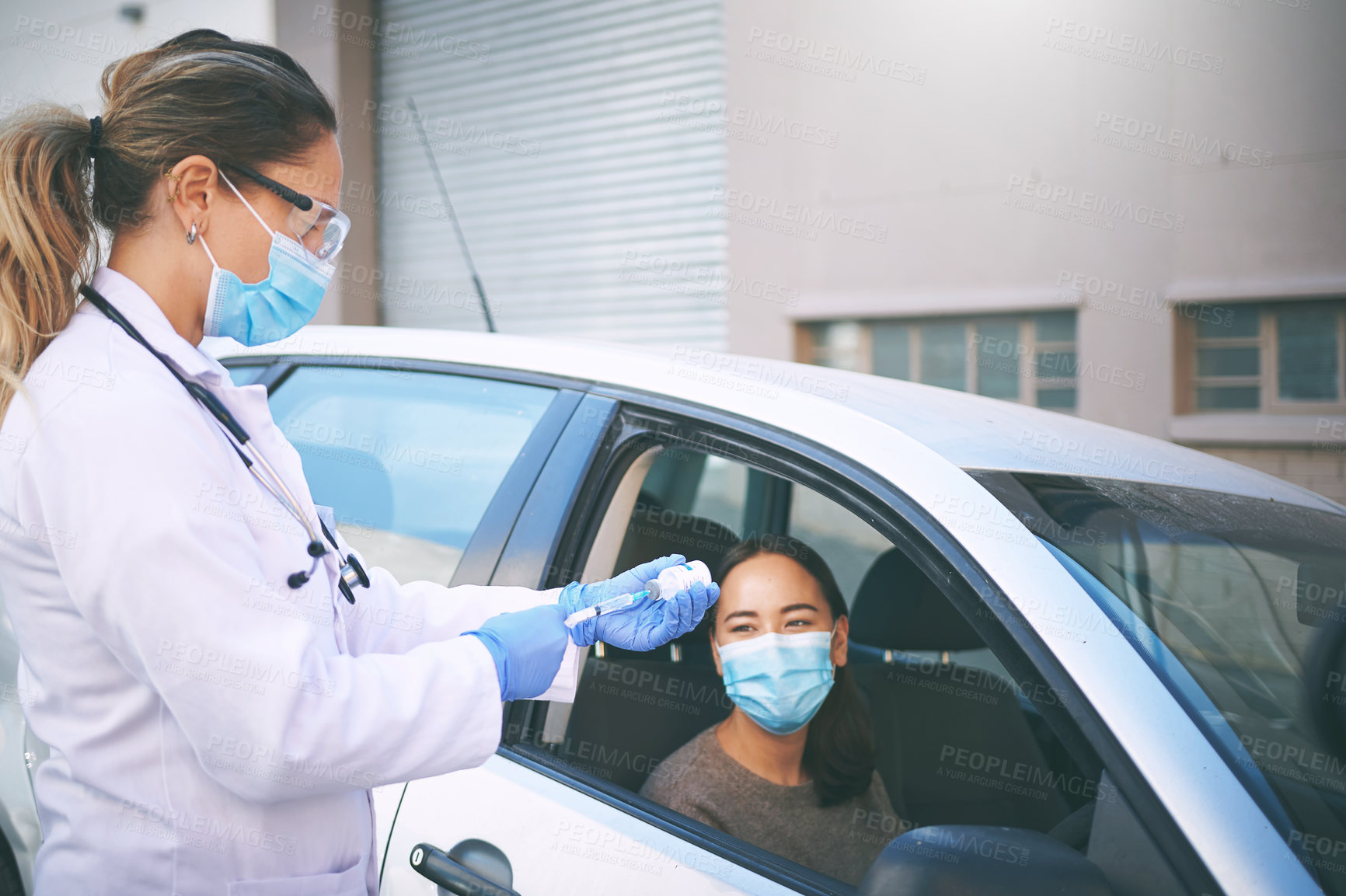 Buy stock photo Shot of a masked young doctor giving a patient an injection at a Covid-19 drive through testing centre