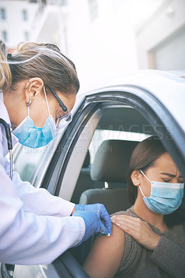 Buy stock photo Shot of a masked young doctor giving a patient an injection at a Covid-19 drive through testing centre