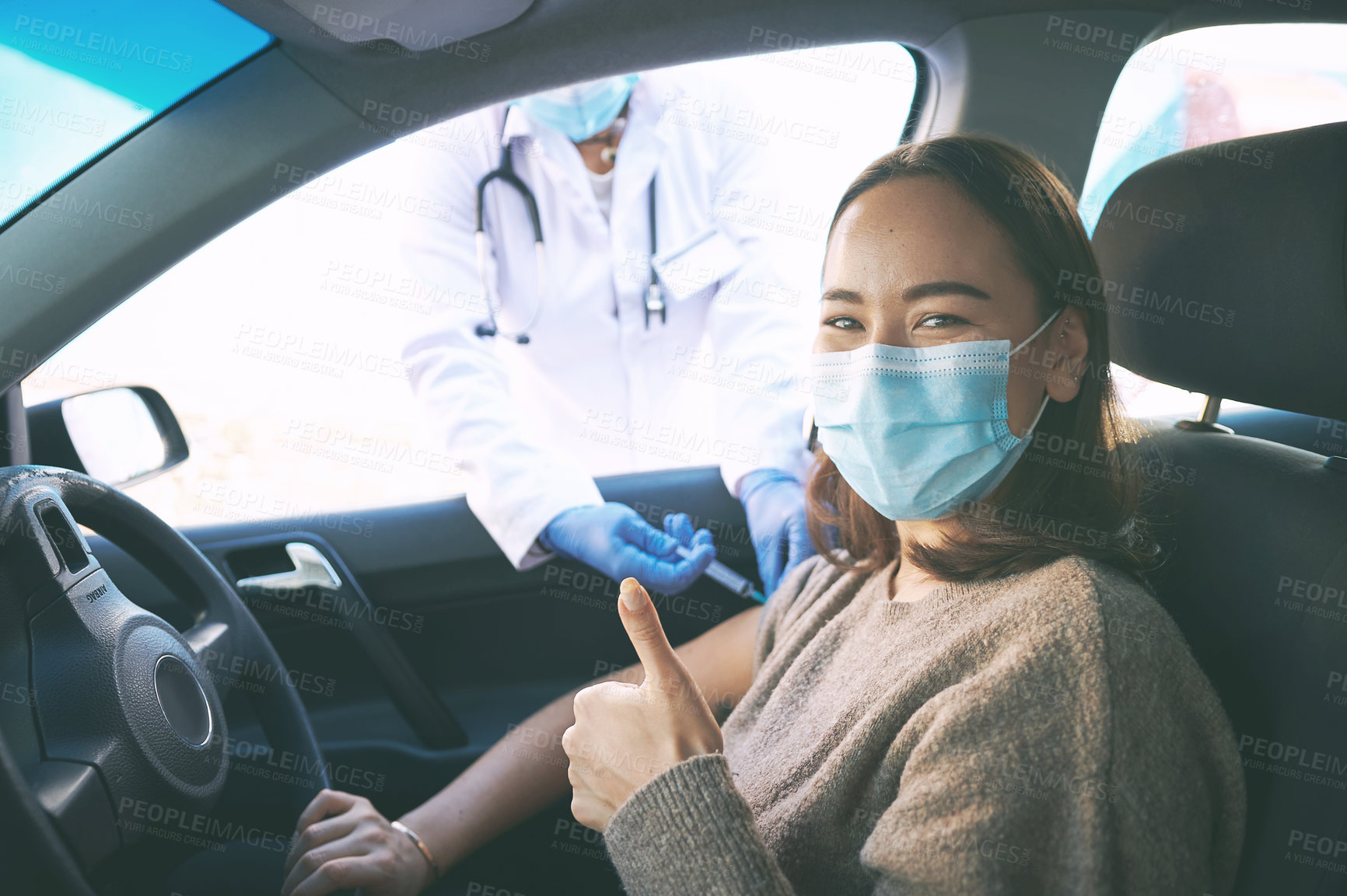 Buy stock photo Shot of a masked young woman receiving an injection at a Covid-19 drive through testing centre