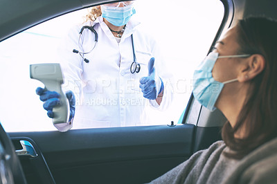 Buy stock photo Shot of a masked young woman getting her temperature checked by a doctor while sitting in her car