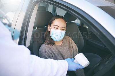Buy stock photo Shot of a masked young woman getting her temperature checked by a doctor while sitting in her car
