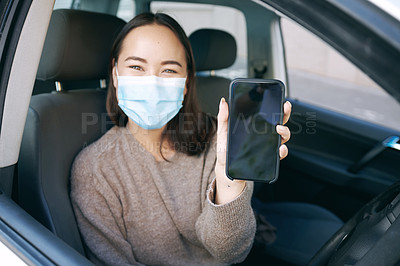 Buy stock photo Shot of a masked young woman showing her smartphone after getting a Covid-19 test in her car at a drive through